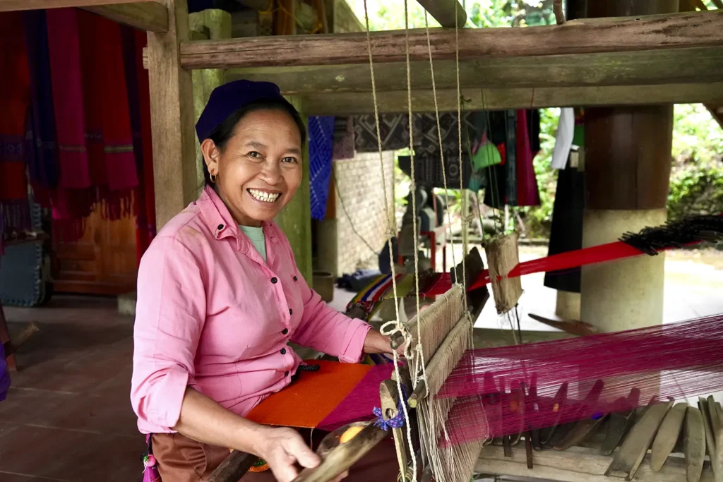 Derrière le métier à tisser Une femme thaïe travaille sur un métier à tisser traditionnel sous une maison sur pilotis à Bản Đôn, Pù Luông.